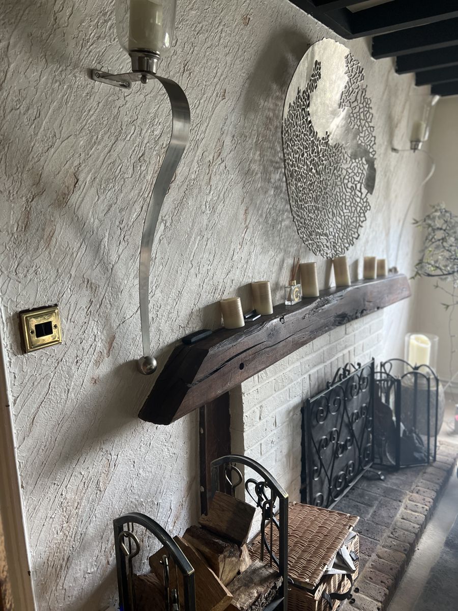 Textured white plaster fireplace wall with oak beam