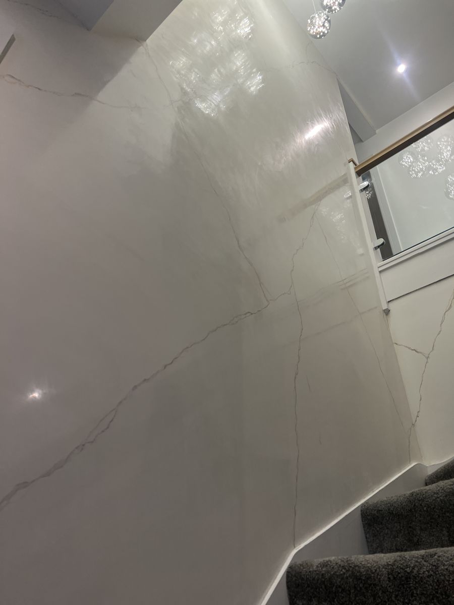 White marble-effect plaster stairwell with a glass pendant light